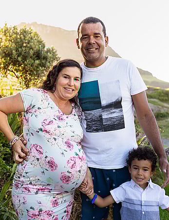 Pregnant woman poses for family photo with her husband and young son