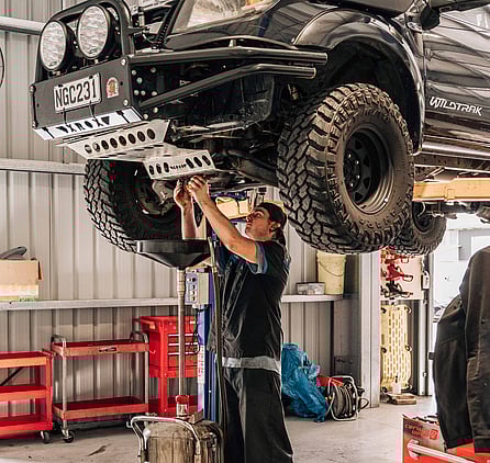 Man changing oil standing under a car