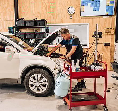 A man working on the air conditioning of a car