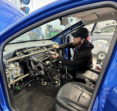A man working on the electrical parts inside a car