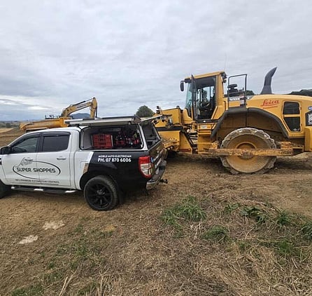 A ute and digger parked in a paddock