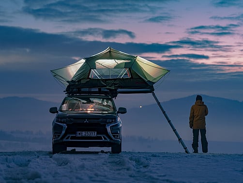 Yakima Skyrise Rooftop tent on a Mitsubishi Outlander in the snow at twilight.