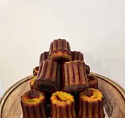 A pile of Caneles. caramelized outsides and fudgy centers.