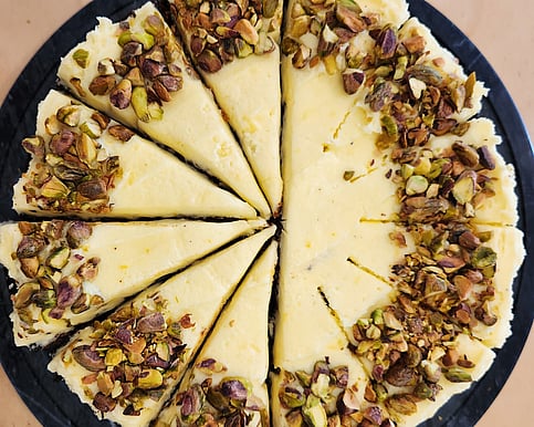 Full carrot cake topped with cream cheese icing and pistachio garnish