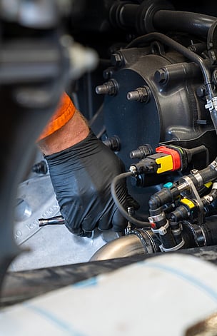 man's hand with glove on working on a heavy truck engine