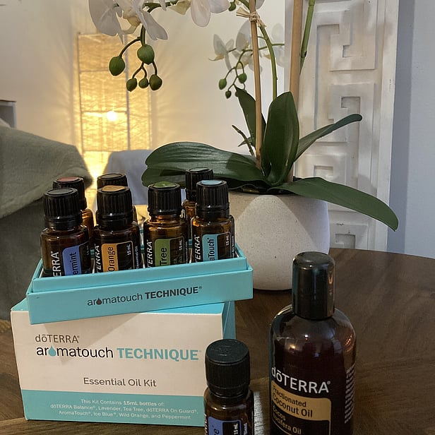 picture of the 8 doterra essential oils on  a table next to an orchard in a massage room and a large light in the corner of the room