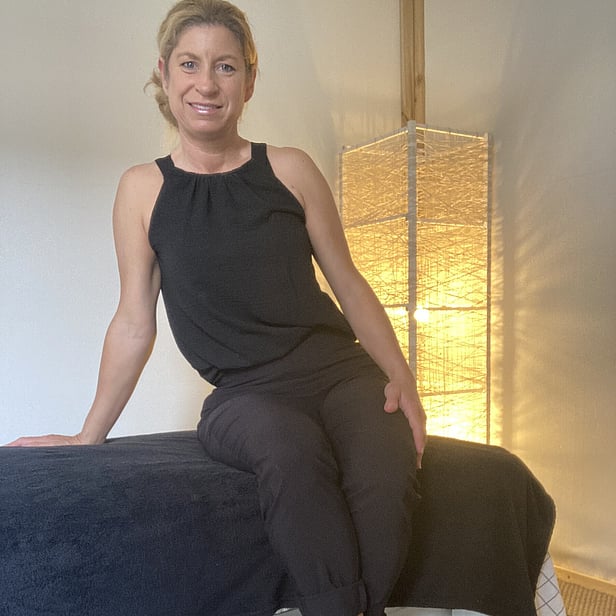 Picture of Sally the massage therapist sitting on the massage table