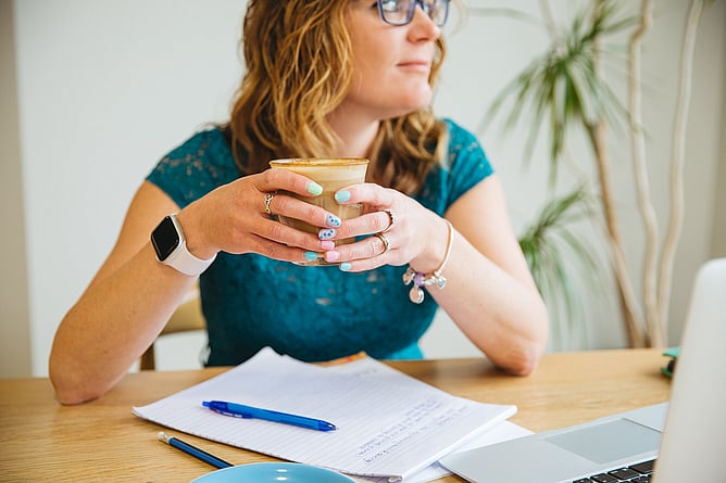 strategic brand designer in a cafe with coffee symbolising how design shapes wedding brand experience and client perception