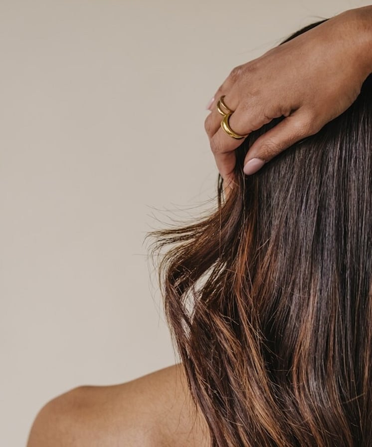 A hand running through dark brown hair as it styles it.