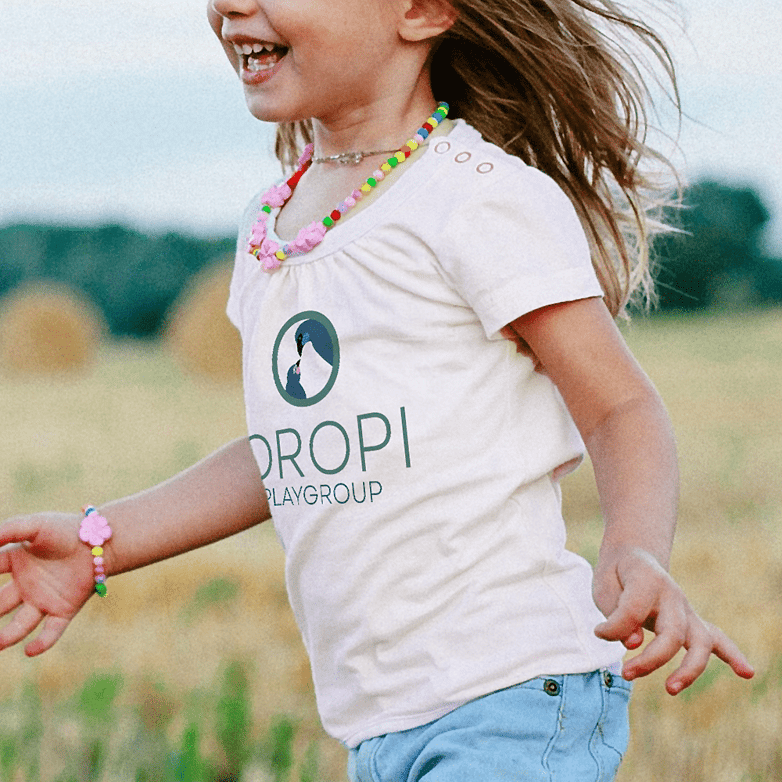 Oropi Playgroup branding on a t-shirt of a young girl running playfully