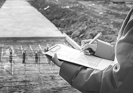 Man's hands holding a clipboard looking at construction work