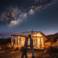 Guests stargazing outside a SkyScape cabin at night