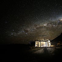 SkyScape cabin illuminated beneath a clear night sky