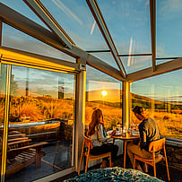 Dining inside a glass-roof cabin at sunset in the Mackenzie Region