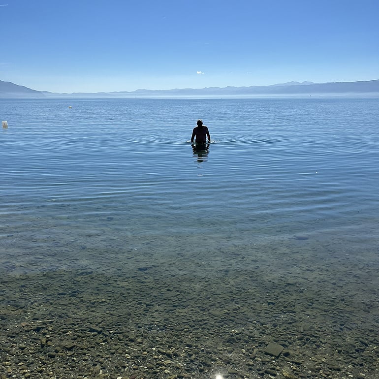 A man standing in the water of Lake Ohrid, walking towards the camera.
