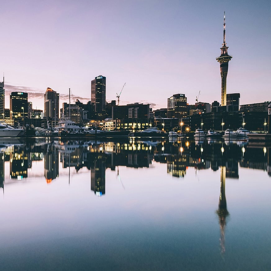 Auckland cityscape at dusk with Sky Tower, boats, and harbour lights