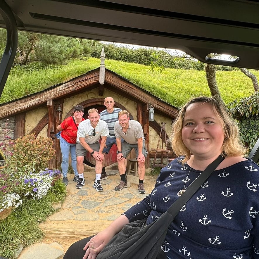 Group of people standing in front of a Hobbiton house in New Zealand