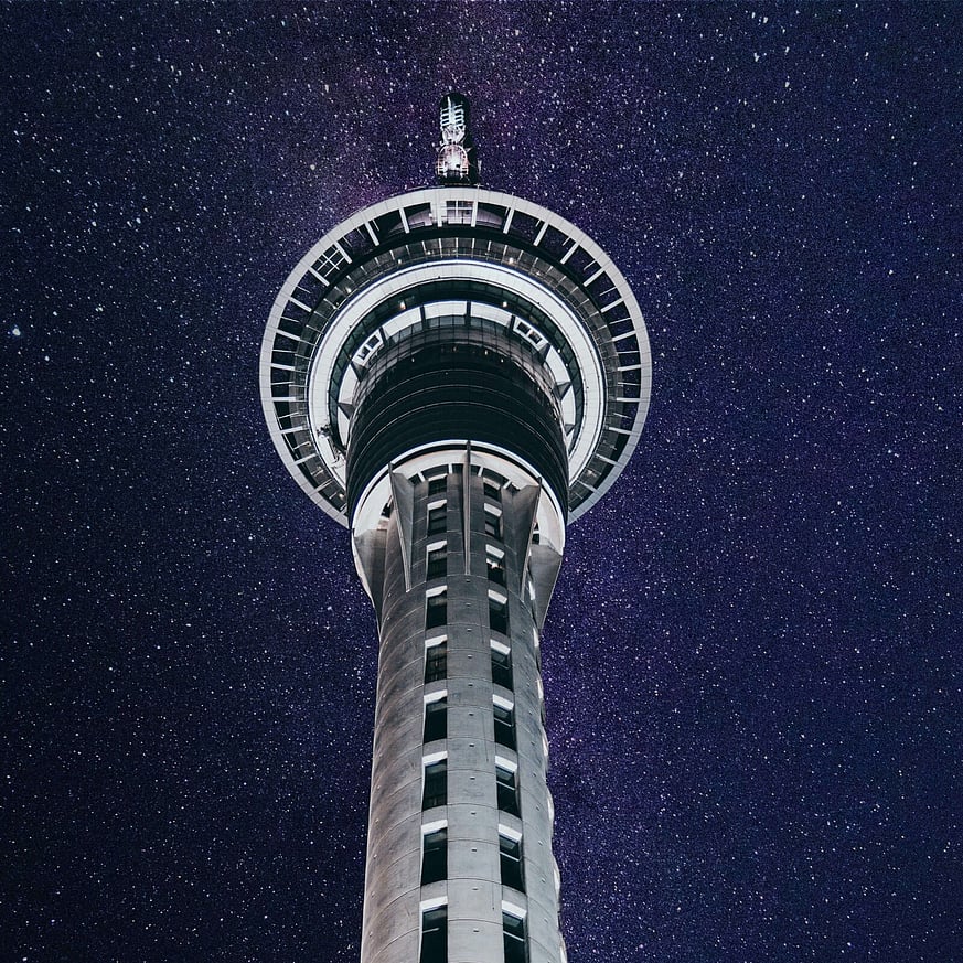 Looking up at Sky Tower at night with stars shining in the sky