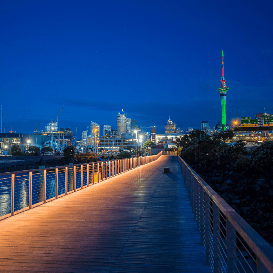 Evening view of a lit-up boardwalk with Sky Tower visible in the background