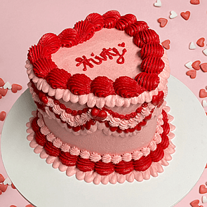 Gluten-free decorative hat shaped cake with pale blue icing cream coloured icing decoration with dark blue green icing silver balls and Lang little bakery text on top