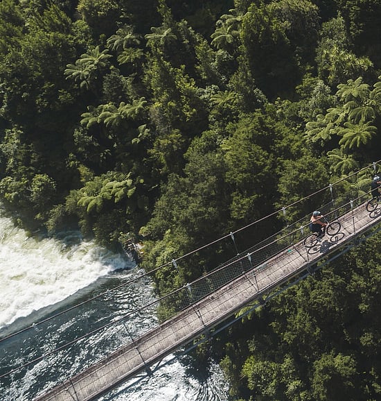 Image of cyclists crossing a river on a suspended bridge