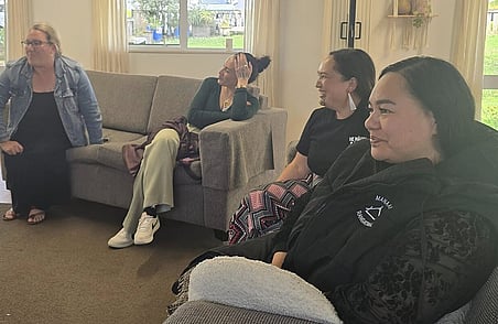 Group of women seated and chatting in relaxed workshop setting with sofa and large windows in background