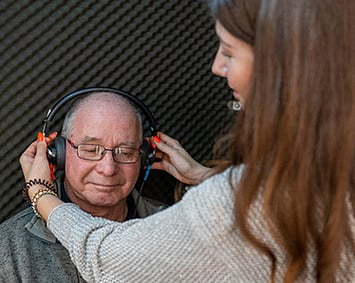 senior man having a hearing test in a soundproof booth at Wolfe hearing