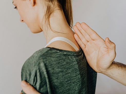Picture for a young girl sitting and the osteopath putting his hand on her back showing her spine