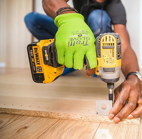 Picture of a person holding an electric drill drilling into a piece of wood