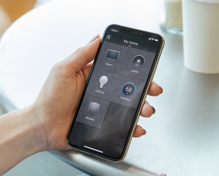 A hand holding a phone with the Control 4 application open on the screen.