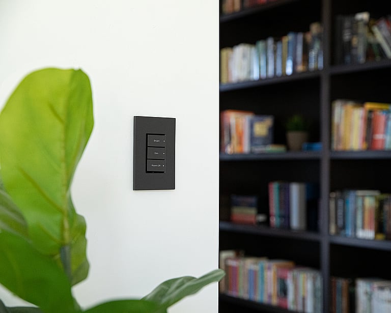 A home library with a light and shade control switch/panel on the wall.