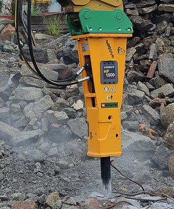An Indeco hydraulic rock breaker or hammer attachment shown breaking up concrete