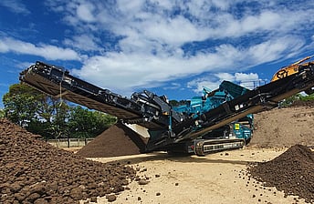 Powerscreen Warrior 1200 screening machine processing soil into different grades using 3 conveyor arms to stockpile the soil grades