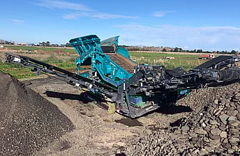 Powerscreen Warrior 1200 screening machine using its 3-way split conveyor arms to stockpile grades of crushed rock