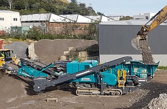 A Powerscreen Trakpactor 260SR rock crushing machine working on crushing waste concrete in a concrete recycling and aggregate supply yard