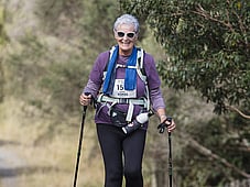 Older woman taking on the course like a boss. Hiking poles and happiness