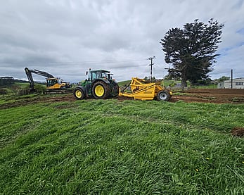 Tractor pulling scraper to start site cut