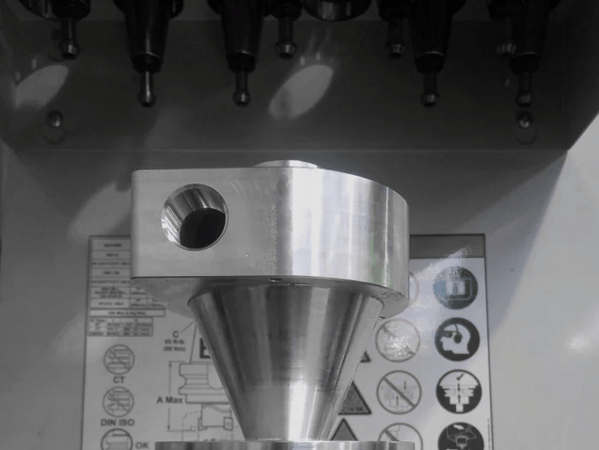 Close-up of CNC-milled aluminium block featuring recessed geometric cavities and sharp internal corners.