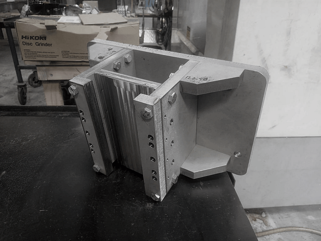 Close-up of CNC-milled aluminium block featuring recessed geometric cavities and sharp internal corners.