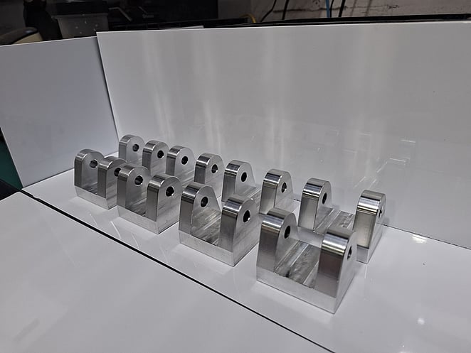 Precision-machined aluminium component with complex contours on a white cloth.