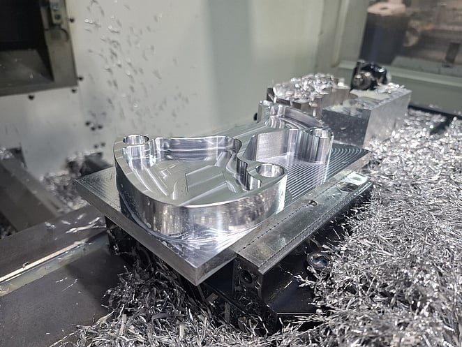 Close-up of CNC-milled aluminium block featuring recessed geometric cavities and sharp internal corners.