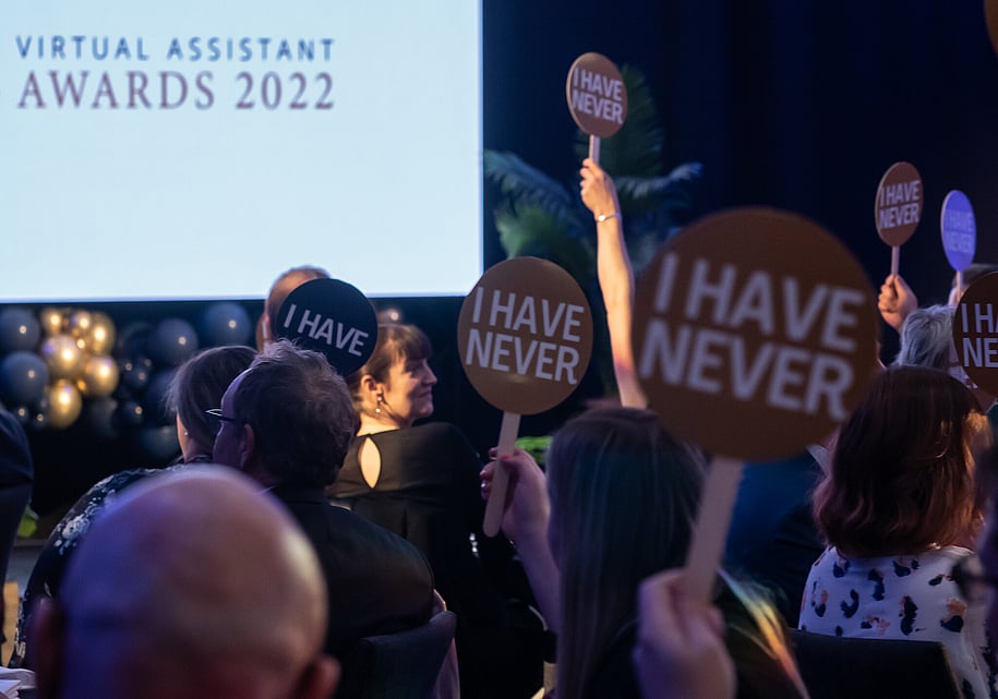 Event guests holding up "never have i ever" game signs during Virtual Assistant Awards in Hamilton, NZ.using 