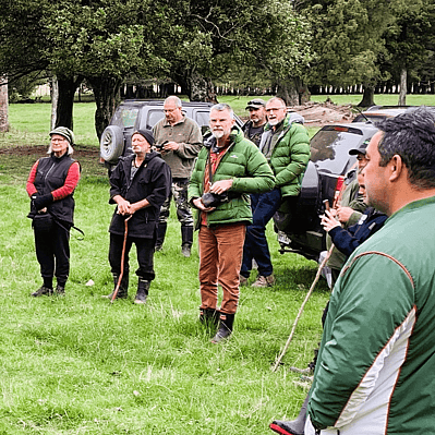Upper Waipoua Kaitiaki catchment group members standing in a paddock listening to a history talk