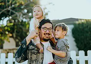 Smiling dad holding 2 children on his shoulders