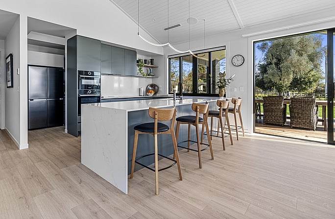 Bespoke modern kitchen has high ceilings, featuring unique white wooden ceiling panels in this award-winning new home.