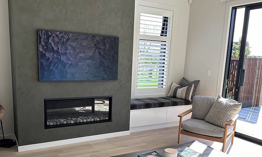 The cosy bay window seat and gas fireplace make this small lounge feel homely in this custom-built house