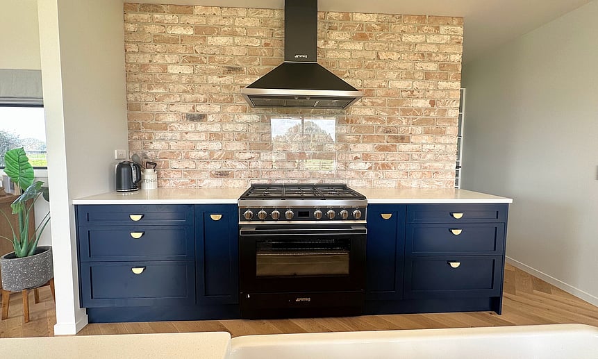 This unique kitchen has a brick wall and custom blue cabinetry makes for a one-of-a-kind design and build.
