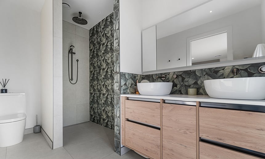 Modern master ensuite features a double vanity, nature-inspired feature tile wall, and luxury walk-in overhead shower.