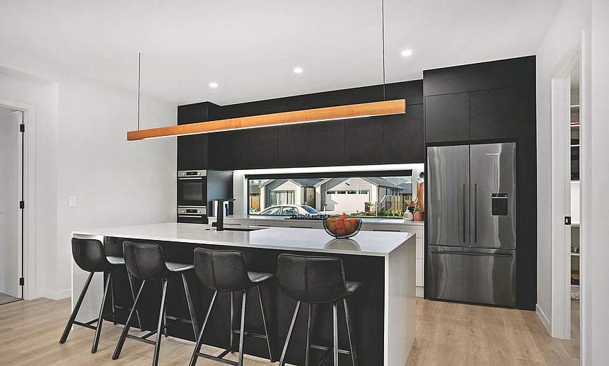 The large stone waterfall island boasts an eat-in bar dining area with stark black stools that has a unique homely style. 