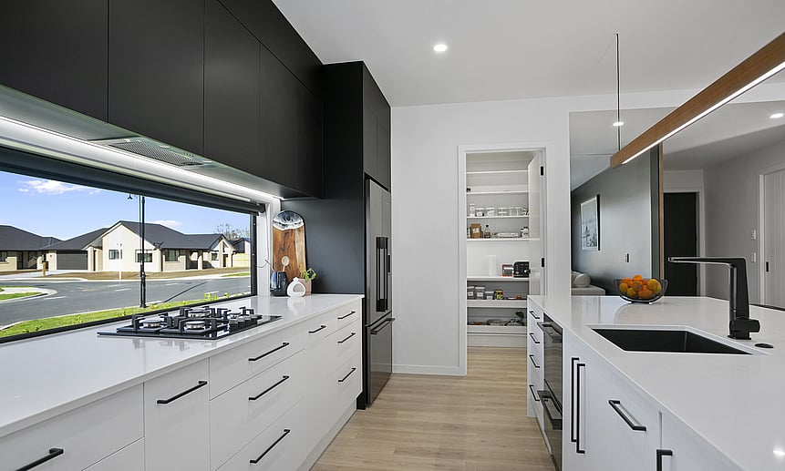 White benchtops and cabinetry with custom black upper cabinetry create a stark contrast, showcasing the custom designed home  
